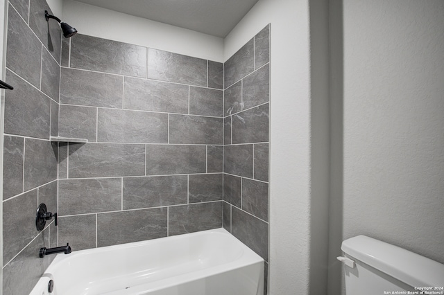 bathroom with toilet and tiled shower / bath combo