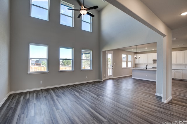 unfurnished living room featuring sink, ceiling fan, a towering ceiling, and dark hardwood / wood-style flooring