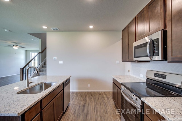 kitchen featuring sink, stainless steel appliances, dark hardwood / wood-style floors, backsplash, and a center island with sink