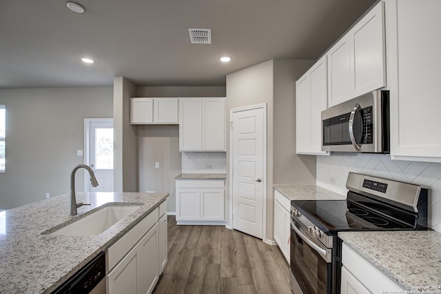 kitchen featuring stainless steel appliances, wood finished floors, visible vents, a sink, and white cabinetry