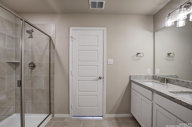 full bathroom with tile patterned floors, a sink, double vanity, a stall shower, and visible vents