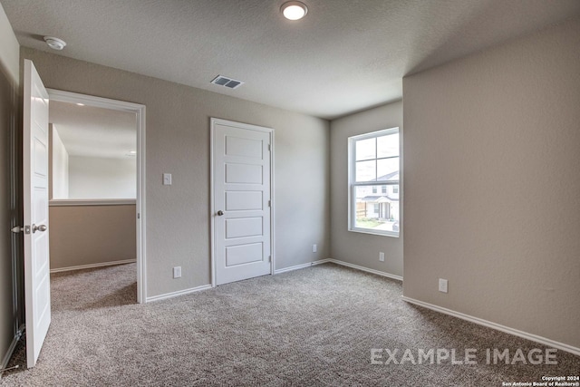 unfurnished bedroom with a textured ceiling and light carpet