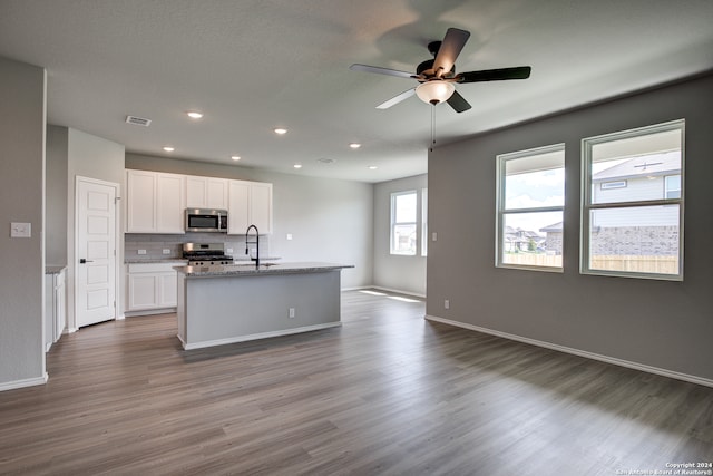 kitchen with sink, appliances with stainless steel finishes, tasteful backsplash, white cabinets, and a center island with sink