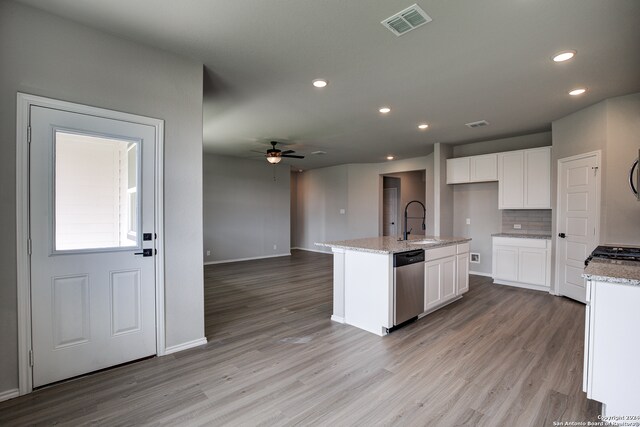 kitchen featuring light stone counters, stainless steel dishwasher, a center island with sink, and white cabinets