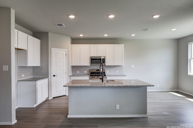 kitchen featuring stainless steel appliances, a kitchen island with sink, and white cabinets