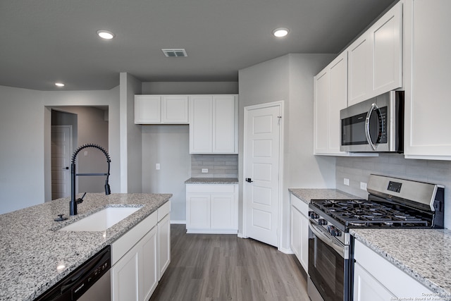 kitchen with sink, light stone countertops, white cabinets, and appliances with stainless steel finishes