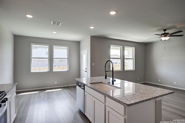 kitchen with sink, white cabinetry, stainless steel appliances, light stone countertops, and a kitchen island with sink