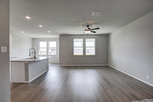 unfurnished living room with ceiling fan, dark hardwood / wood-style floors, sink, and a textured ceiling