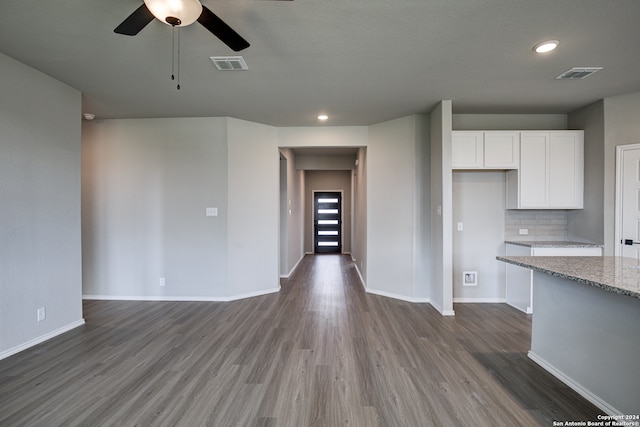 kitchen featuring dark hardwood / wood-style floors, tasteful backsplash, white cabinets, ceiling fan, and light stone countertops