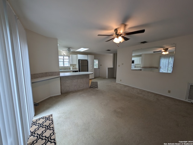 unfurnished living room featuring ceiling fan and light carpet