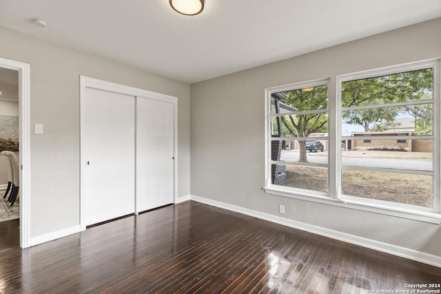 unfurnished bedroom with dark hardwood / wood-style floors and a closet