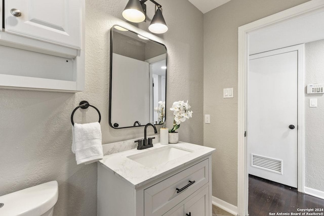 bathroom featuring vanity, hardwood / wood-style flooring, and toilet