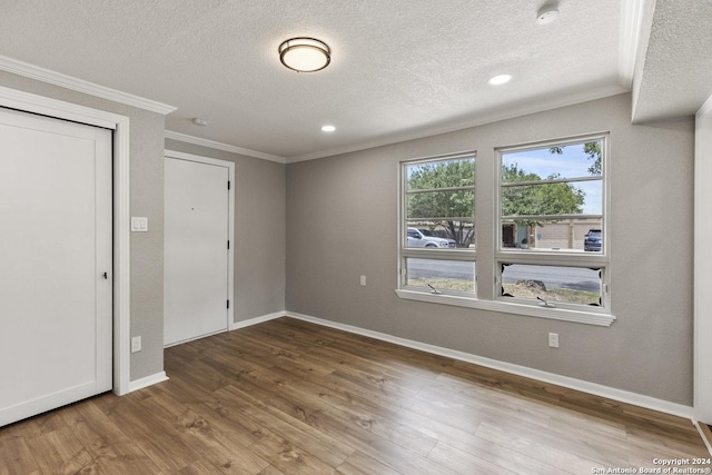 spare room featuring wood-type flooring, a textured ceiling, and ornamental molding