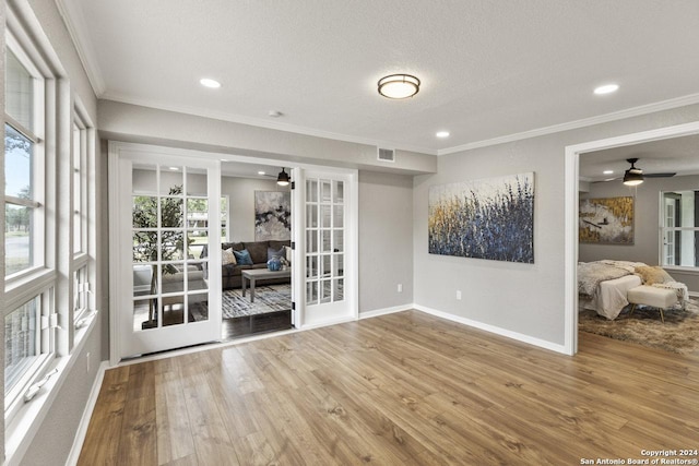 empty room with french doors, hardwood / wood-style flooring, and ornamental molding