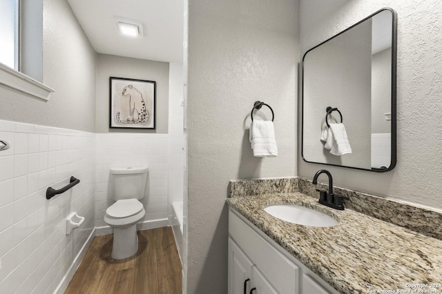 bathroom with hardwood / wood-style flooring, vanity, toilet, and tile walls