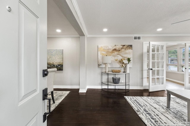 interior space with a textured ceiling, crown molding, dark wood-type flooring, and french doors