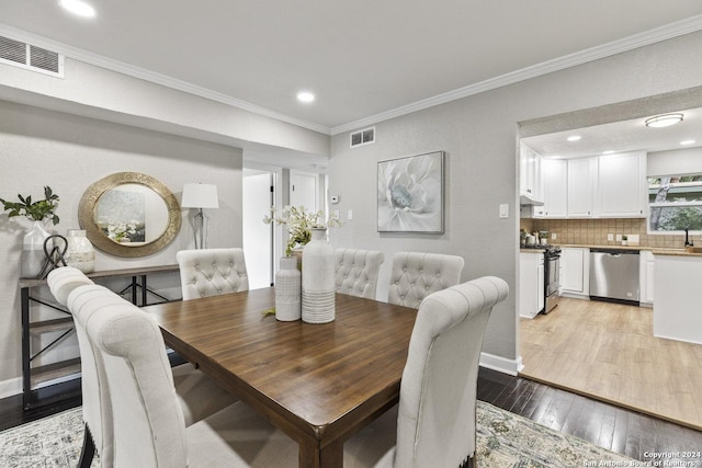 dining space featuring sink, ornamental molding, and light wood-type flooring