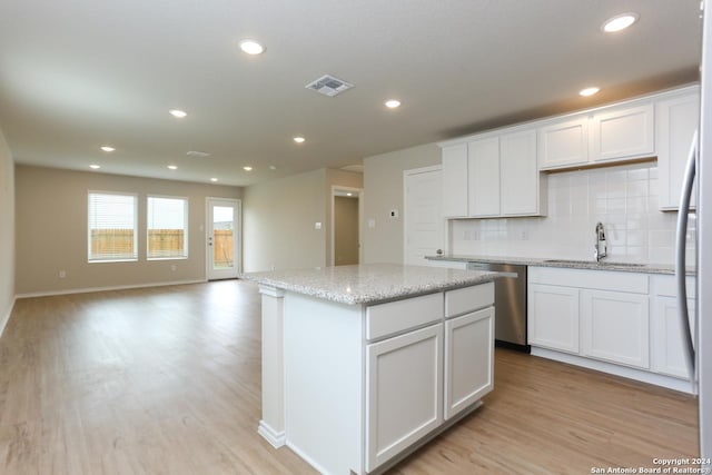 kitchen featuring dishwasher, sink, decorative backsplash, light stone countertops, and white cabinetry