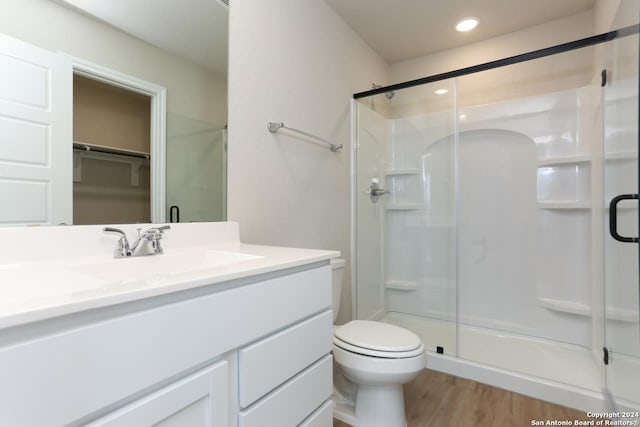 bathroom featuring hardwood / wood-style floors, vanity, a shower with shower door, and toilet