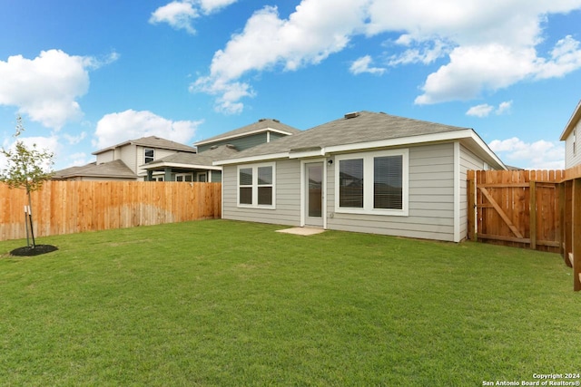 rear view of property featuring a lawn