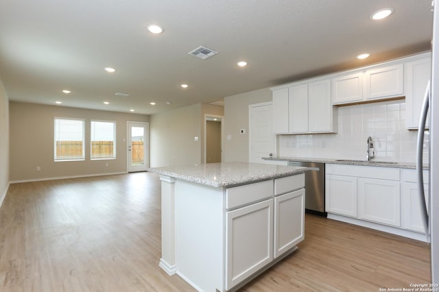 kitchen with light stone countertops, white cabinetry, sink, tasteful backsplash, and stainless steel dishwasher