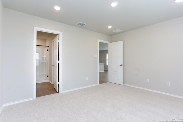 unfurnished bedroom with ensuite bathroom and light colored carpet