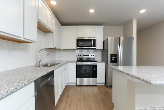 kitchen with decorative backsplash, appliances with stainless steel finishes, sink, light hardwood / wood-style flooring, and white cabinets