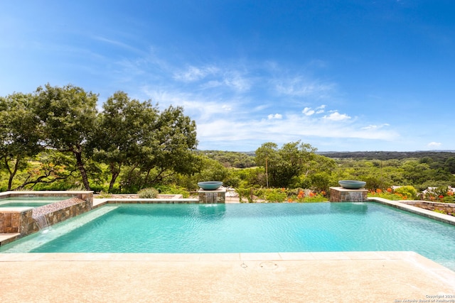 view of pool featuring pool water feature and an in ground hot tub