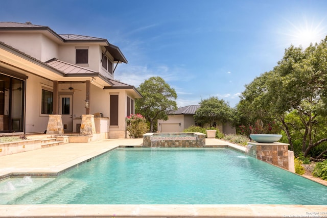 view of pool with ceiling fan, an in ground hot tub, pool water feature, exterior kitchen, and a patio