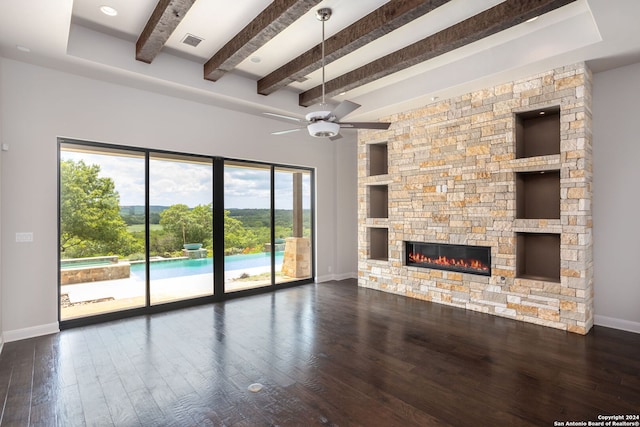 unfurnished living room featuring ceiling fan, dark wood-type flooring, beam ceiling, and a stone fireplace