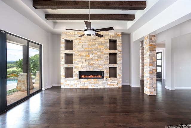 unfurnished living room with ceiling fan, a stone fireplace, built in shelves, dark hardwood / wood-style floors, and beamed ceiling