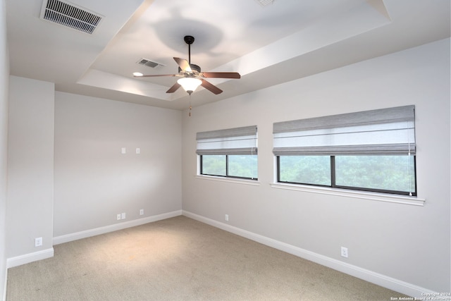 carpeted spare room with ceiling fan and a raised ceiling