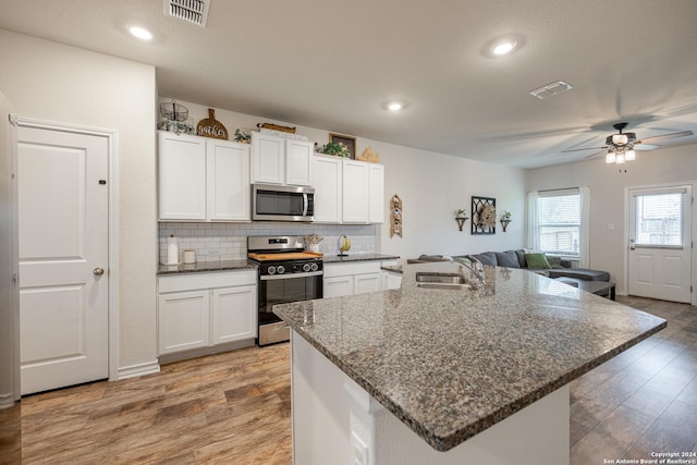 kitchen featuring stainless steel appliances, an island with sink, sink, and white cabinetry