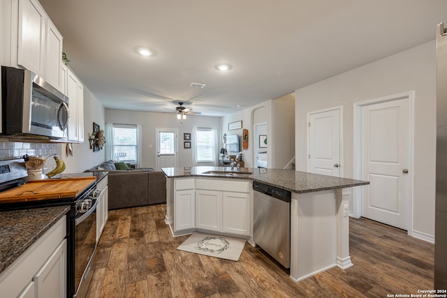 kitchen featuring dark hardwood / wood-style floors, ceiling fan, dark stone countertops, white cabinets, and appliances with stainless steel finishes