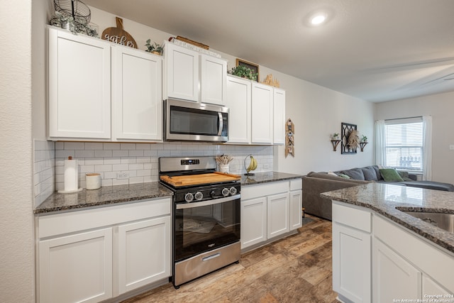 kitchen featuring hardwood / wood-style flooring, white cabinets, backsplash, and stainless steel appliances