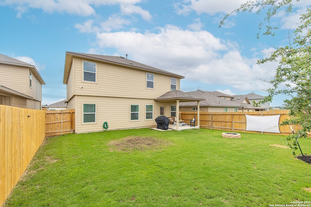 back of house with a yard, an outdoor fire pit, and a patio