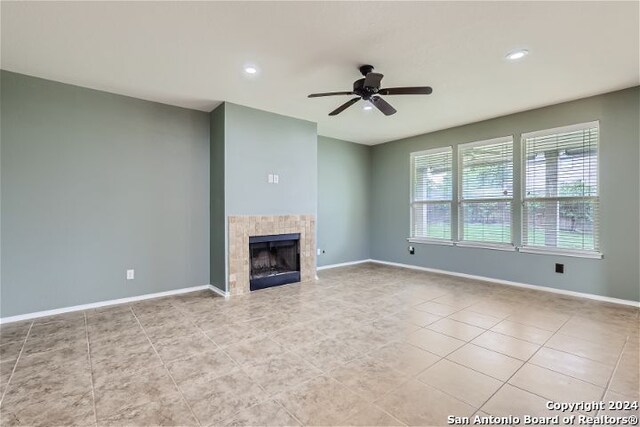 unfurnished living room with ceiling fan, light tile patterned floors, and a fireplace