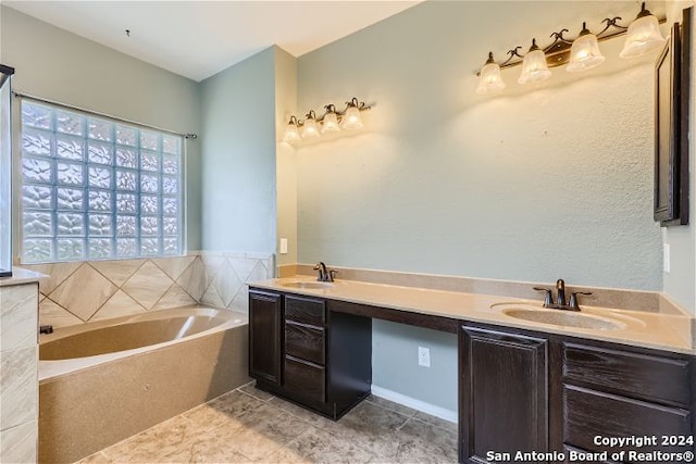 bathroom featuring a relaxing tiled tub, tile patterned floors, and vanity