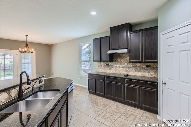 kitchen featuring backsplash, a notable chandelier, sink, hanging light fixtures, and light tile patterned floors