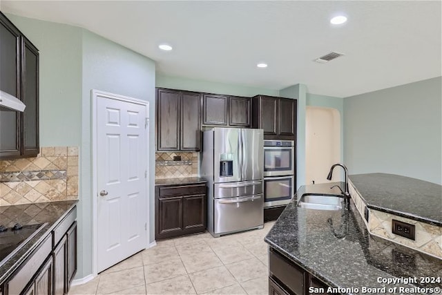 kitchen with light tile patterned floors, appliances with stainless steel finishes, tasteful backsplash, and sink