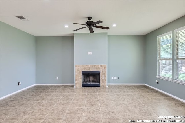 unfurnished living room featuring ceiling fan, light tile patterned floors, and a tile fireplace