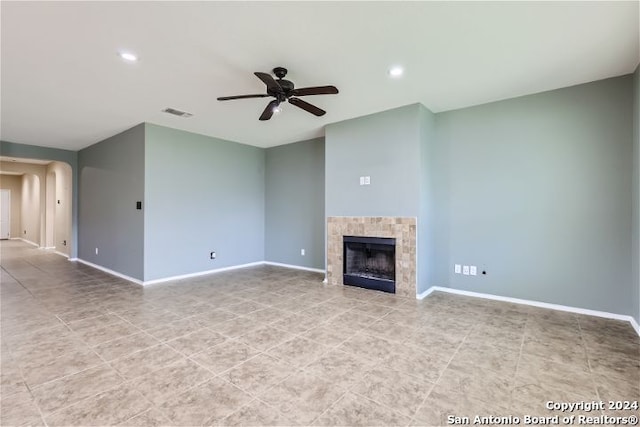 unfurnished living room with ceiling fan and a tiled fireplace