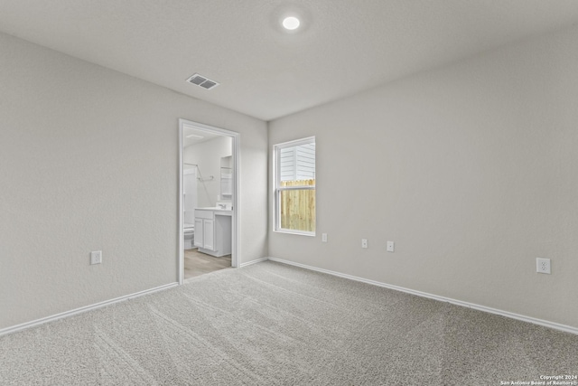 unfurnished bedroom featuring light colored carpet and ensuite bathroom