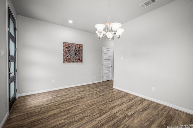 empty room featuring dark hardwood / wood-style flooring and a chandelier