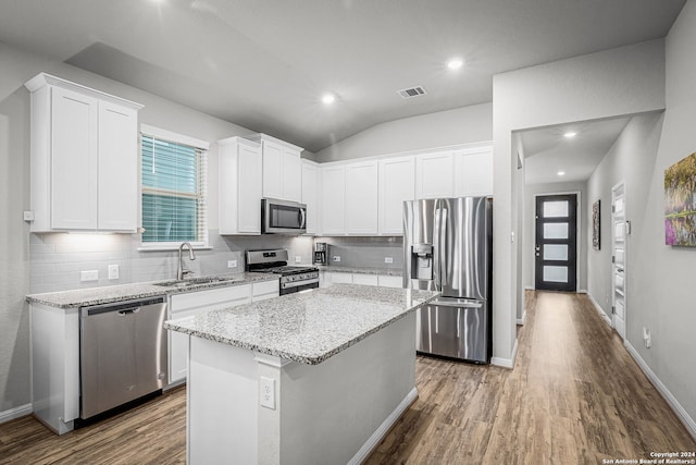 kitchen with appliances with stainless steel finishes, light stone counters, a kitchen island, sink, and white cabinetry