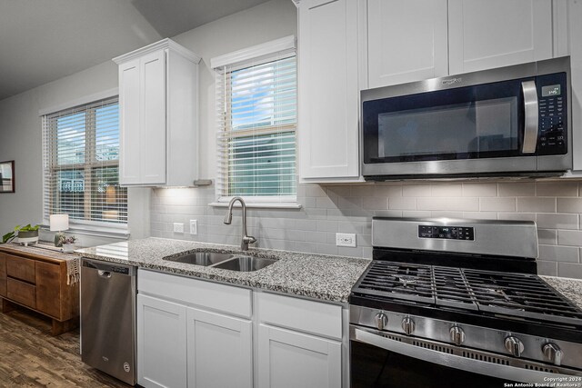 kitchen with decorative backsplash, stainless steel appliances, white cabinetry, and sink