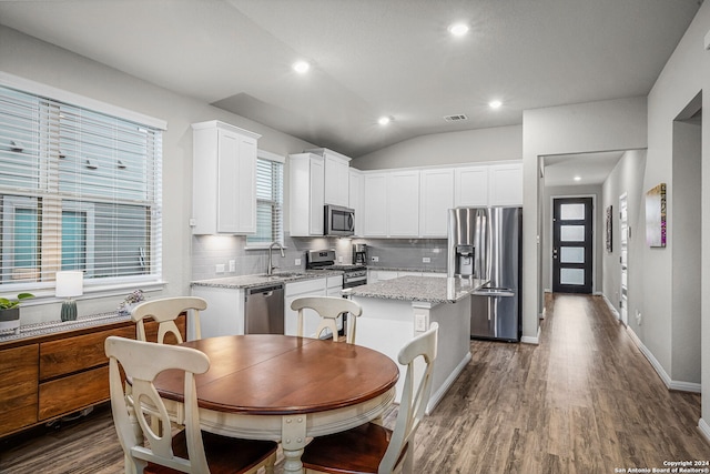 kitchen with a center island, decorative backsplash, light stone counters, white cabinetry, and stainless steel appliances