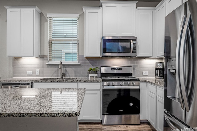 kitchen featuring light stone counters, stainless steel appliances, white cabinetry, and sink