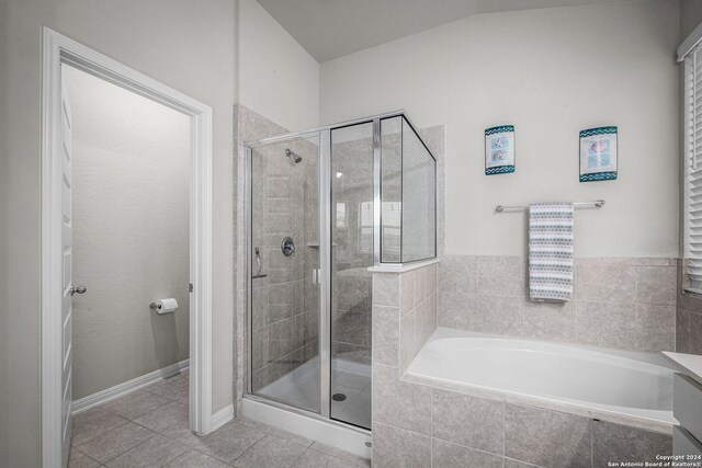 bathroom featuring tile patterned flooring, shower with separate bathtub, and vaulted ceiling