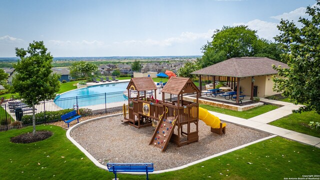 view of playground featuring a fenced in pool, a patio area, and a lawn